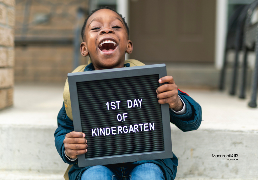 Child holding kindergarten sign — take our kindergarten readiness quiz